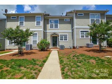 Inviting exterior of townhome featuring manicured lawn and walkway to front door at 105 Woodsong Ln, Mooresville, NC 28117
