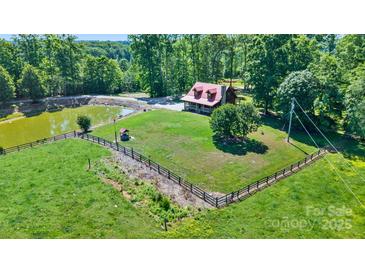 Stunning aerial view of a charming home with a pond, surrounded by lush greenery and a fenced yard at 11227 Cool Springs Rd, Cleveland, NC 27013
