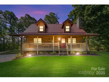 Charming log cabin home featuring a metal roof, covered front porch, and manicured lawn at 11227 Cool Springs Rd, Cleveland, NC 27013