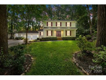 Charming two-story home with a manicured lawn, lush landscaping, and a detached garage with ample parking at 201 Scalybark Trl, Concord, NC 28027