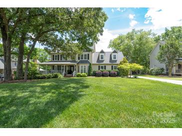 Traditional two-story home featuring a large front yard, covered porch, mature trees, and inviting curb appeal at 503 New Castle Ne Ct, Concord, NC 28025