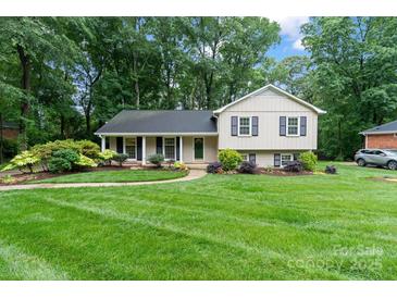 Charming home with a manicured lawn, mature trees, and a welcoming front entrance at 6208 Rocky Falls Rd, Charlotte, NC 28211