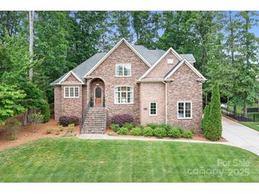 Charming brick home with a well-manicured lawn, mature trees, and inviting front entrance at 7738 Burning Ridge Dr, Stanley, NC 28164