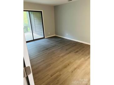 Bright bedroom with wood-look flooring and sliding glass doors leading to outdoor space at 8029 Cedar Glen Dr, Charlotte, NC 28212