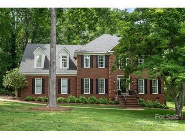 Charming two-story brick home with black shutters and a well-manicured lawn nestled among mature trees at 915 Waterview Ln, Monroe, NC 28110