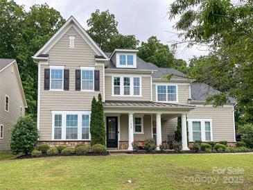 Charming two-story home featuring neutral siding, black shutters, covered porch and lush, well-maintained landscaping at 11216 Preservation Ln, Charlotte, NC 28278