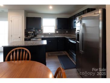 Modern kitchen features black cabinets, stainless steel appliances, and granite countertops at 116 Crownpiece St, Troutman, NC 28166