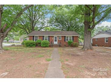 Charming brick home with black shutters, lush trees, and a walkway leading to the front door at 1320 Hartford Ave, Charlotte, NC 28209