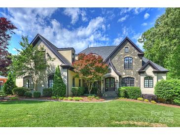 Stunning stone and stucco home with manicured lawn and mature trees, showcasing curb appeal at 2004 Garden View Ln, Weddington, NC 28104