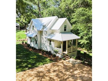 Beautiful two-story home featuring a white exterior, metal roof, manicured lawn, and landscaped yard at 2268 New Gray Rock Rd, Fort Mill, SC 29708