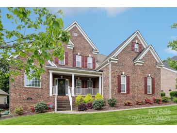 Charming two-story brick home with red shutters, a covered porch, and well-maintained landscaping at 9034 Kensington Forest Dr, Harrisburg, NC 28075