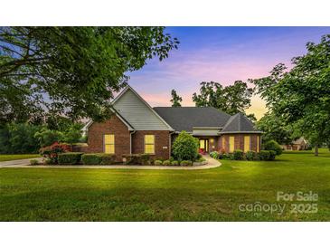 Inviting brick home with manicured lawn, lush landscaping and charming curb appeal with mature trees at 1825 Smyre Farm Rd, Newton, NC 28658