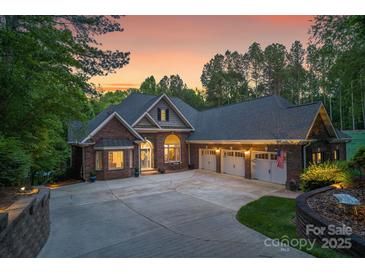 Stunning brick home with a three-car garage and a circular driveway at dusk at 2200 Capes Cove Dr, Sherrills Ford, NC 28673