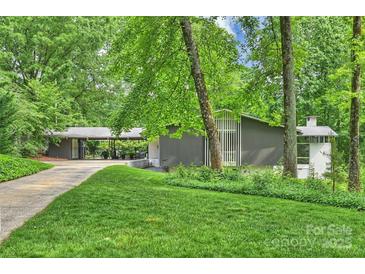 Stunning exterior of mid-century modern home with lush landscaping and gray painted facade at 447 Merwick Cir, Charlotte, NC 28211