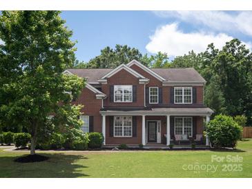 Charming two-story brick home featuring classic shutters, a covered front porch, and a well-manicured lawn at 6309 Crosshall Pl, Waxhaw, NC 28173