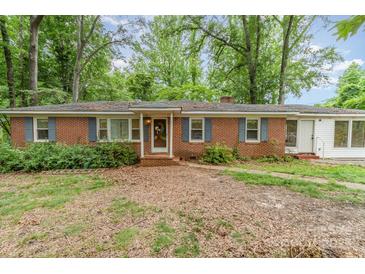 Cozy brick home featuring blue shutters and a charming front yard surrounded by mature trees at 6934 Lockhart Rd, Sharon, SC 29742