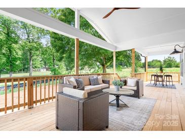 Inviting covered patio featuring wicker furniture, ceiling fan, and view of the lush backyard at 104 Arbor Dr, Waxhaw, NC 28173