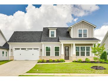 Charming two-story home with a manicured lawn, attached garage, and inviting front porch at 13702 Tranquil Day Dr, Matthews, NC 28105
