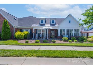 Charming brick home with a manicured lawn, black fence, and inviting front porch seating area at 148 Adelaide Way, Rock Hill, SC 29732