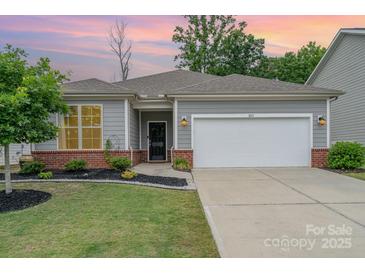 Charming single-story home with a two-car garage, manicured lawn, and brick accents at dusk at 1813 Shelbourne Way, Fort Mill, SC 29707
