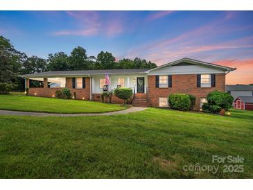 Charming brick home with manicured lawn, welcoming front porch, and patriotic American flag at 2968 Grace St, Claremont, NC 28610