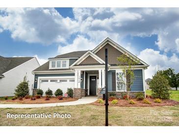 Charming single-Gathering home with blue siding, stone accents, and a well-manicured front lawn at 3315 Whispering Creek Dr # 95, Wesley Chapel, NC 28079