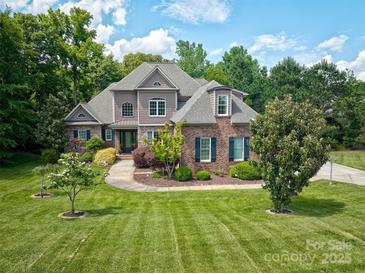 Beautiful brick home with a landscaped yard, mature trees and a curved walkway leading to the front door at 5826 Natoma Rd, Lake Wylie, SC 29710