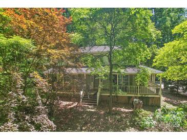 Two-story home with a covered front porch surrounded by lush greenery and mature trees at 8504 Knollwood Cir, Charlotte, NC 28213