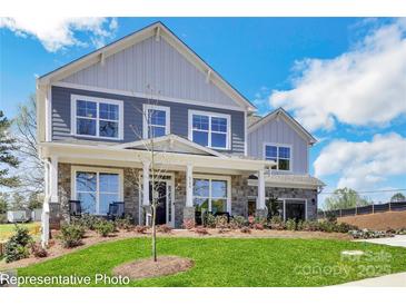 Charming two-story home with a landscaped yard, stone accents, and inviting front porch with rocking chairs at 8692 Acadia Pkwy # 591, Sherrills Ford, NC 28673