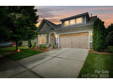 Charming two-story home with a two car garage and landscaped front yard against a warm sunset at 8818 Artesa Mill Ln, Charlotte, NC 28214