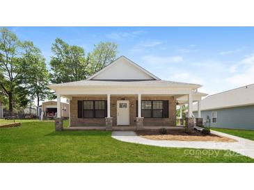Charming brick home with a inviting front porch and a well-manicured lawn at 507 E Cloninger St, Dallas, NC 28034