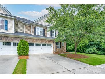 Charming townhome with a two-car garage, stone accents, and well-maintained landscaping at 11945 Red Rust Ln, Charlotte, NC 28277
