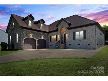 Stunning stone and brick home featuring a two-car garage, arched entrance, and well-manicured lawn at 1974 Glen Manor Ct, Lincolnton, NC 28092