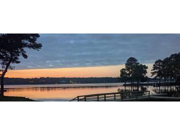 Scenic lake view featuring a serene waterfront, wooden dock, and a colorful sunset, perfect for lakeside living at 3911 Sandy Point Dr, York, SC 29745