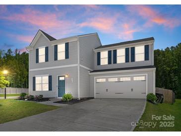 Charming two-story home with light gray siding, dark blue shutters, and a well-manicured lawn at twilight at 110 Browband St, Troutman, NC 28166