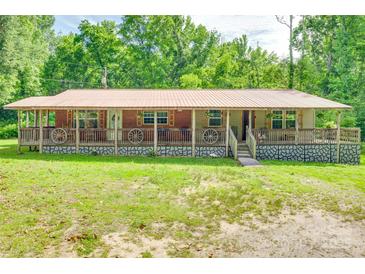 Charming single-story home with a metal roof, inviting front porch, and decorative wagon wheel accents at 3988 Old Hickory Rd, Lancaster, SC 29720