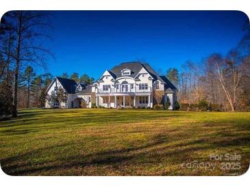 Expansive estate featuring a large lawn, balconies, and a stately facade under a bright blue sky at 450 Greywalls Ln, Iron Station, NC 28080