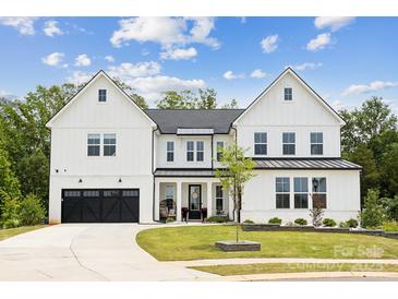 Stunning two-story white farmhouse-style home with a black garage door and beautifully landscaped front yard at 4530 Tournette Dr # 18, Indian Land, SC 29707