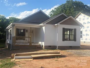 Charming single-story home with white siding, dark shutters, covered porch and architectural details at 626 W Bell St, Statesville, NC 28677