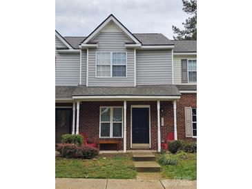 Charming townhome featuring a brick facade, covered porch, and inviting curb appeal with colorful chairs and plantings at 7562 Petrea Ln, Charlotte, NC 28227
