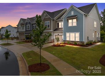 Charming townhome exterior featuring colorful siding, well-manicured landscaping, and attached garage at 8215 Houser St, Cornelius, NC 28031