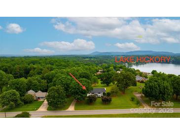 Expansive view of the lake house featuring lush greenery and a glimpse of Lake Hickory at 827 River Hills Ct, Taylorsville, NC 28681