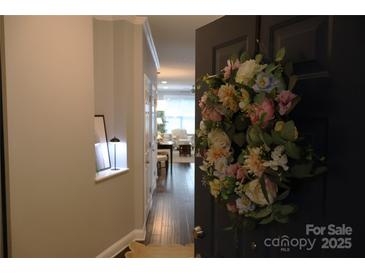 Inviting entryway with wood floors and a charming floral wreath adorning the front door at 1000 E Woodlawn Rd # 107, Charlotte, NC 28209