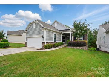 Charming home featuring a two-car garage, stone accents, manicured lawn, and lush landscaping at 1030 Pinehurst Ln, Fort Mill, SC 29707