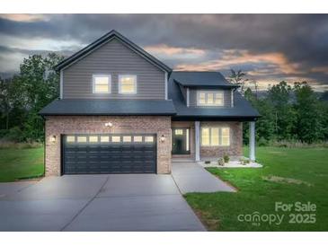 Charming two-story home with a brick facade, black garage door, and well-manicured lawn at dusk at 207 9Th Ne Ct, Conover, NC 28613