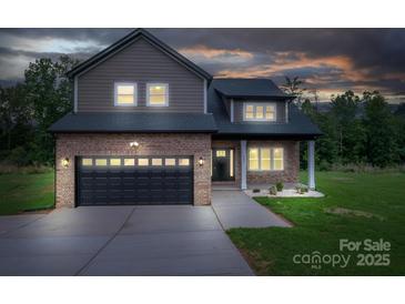 Charming two-story home with brick and siding exterior, featuring an attached garage and manicured front lawn at 207 9Th Ne Ct, Conover, NC 28613
