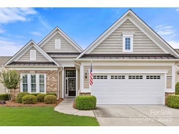 Charming home featuring brick and shingle accents, a two-car garage and manicured landscaping at 7036 Kitty Hawk Ln, Fort Mill, SC 29707