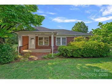 Charming single-story brick home featuring a cozy front porch and well-maintained landscaping at 1000 Peachtree Rd, Charlotte, NC 28216