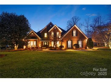 Charming brick home exterior featuring a manicured lawn and professional landscaping at twilight at 3115 Duck Point Dr, Monroe, NC 28110