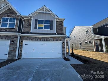 Two-story townhome features stone accents, a two-car garage, and an 'available' sign in the upper window at 4131 Black Ct # 170, Harrisburg, NC 28075